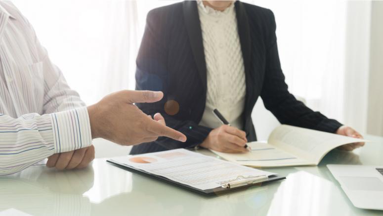 two people at a table in front of documents