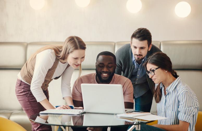 A group of people look at a computer together.