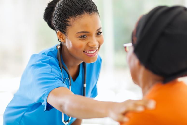 A care provider smiles and reaches out to a patient.