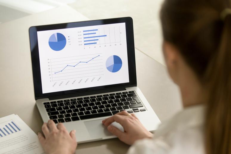 A woman looking at charts on a laptop.