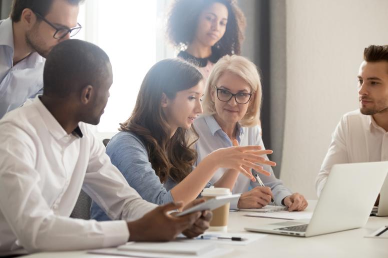 A team discusses around a lap top.