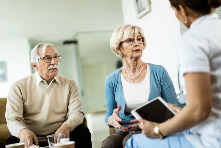 older couple meeting with a doctor, both of them looking at paperwork.