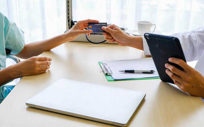 patient paying for care and handing a credit card over to a medical professional 