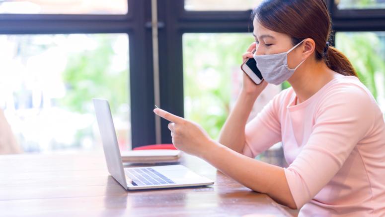 Asian woman in a mask paying a medicial bill