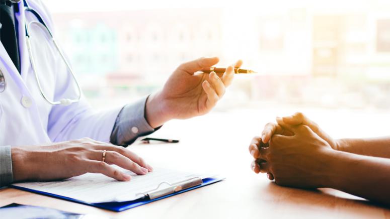 physician hands with pen and patient hands at table