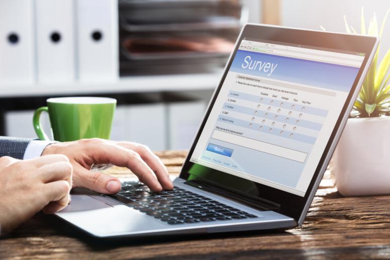 laptop with survey on screen and two hands