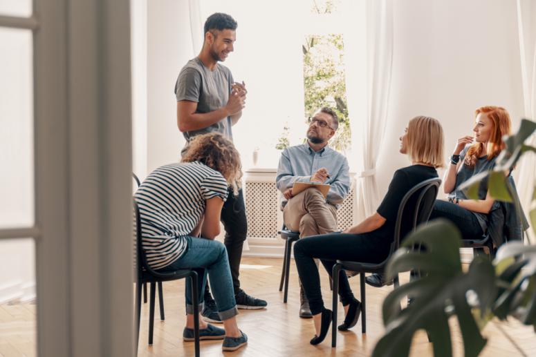 Happy hispanic man talking to his support group about his successful fight with drug addiction