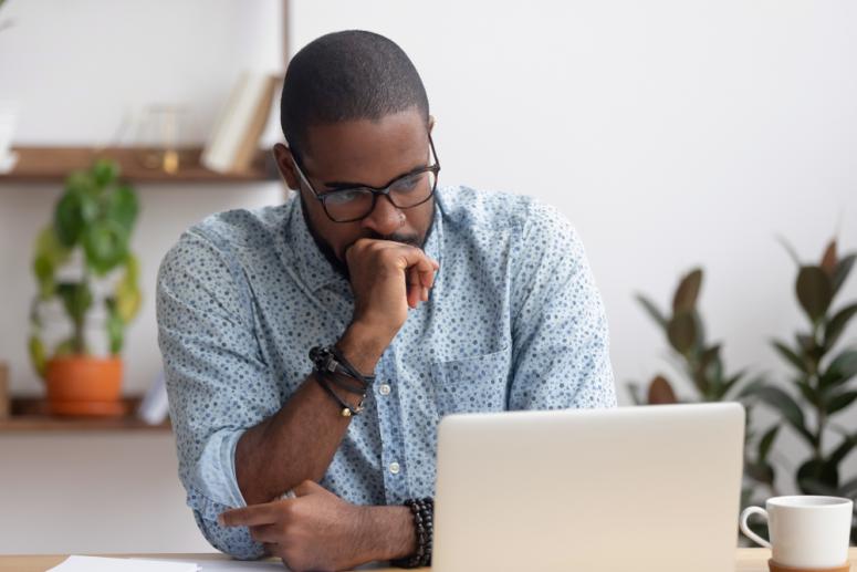 frustrated black man looking at computer screen