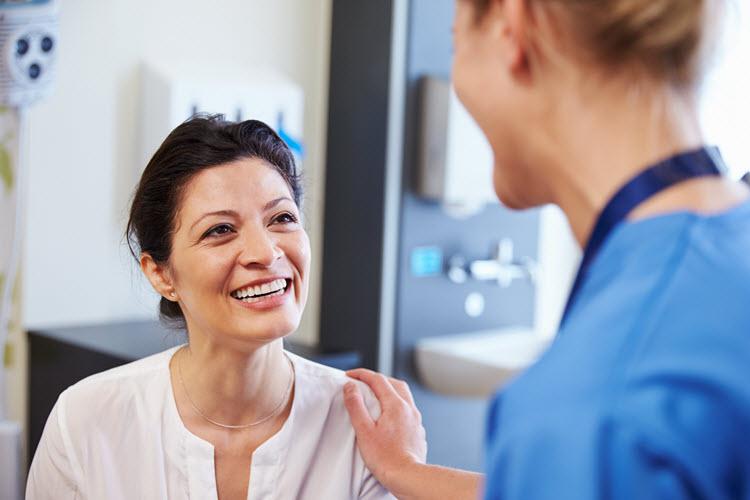 woman with doctor's hand on her shoulder smiling