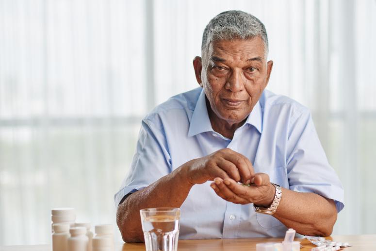 Portrait of elderly Indian man taking medicine every day